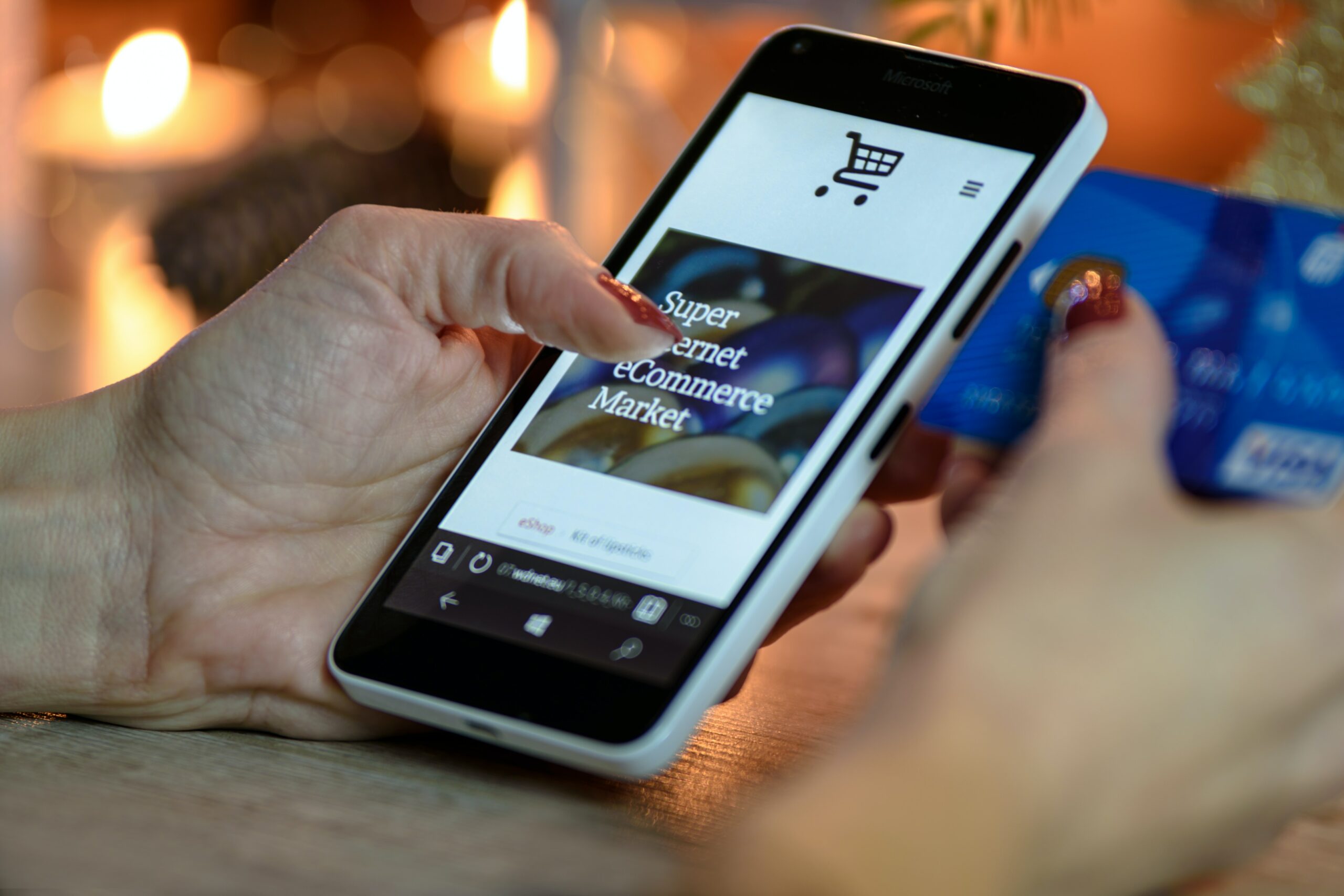 Person using black and white smartphone and holding a blue credit card