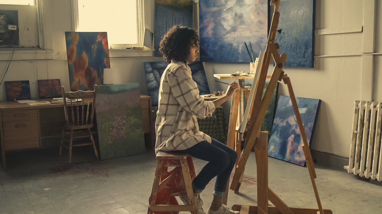 A woman paints on a canvas in an art studio. Utilize your creativity in entrepreneurship to optimize your business' potential.