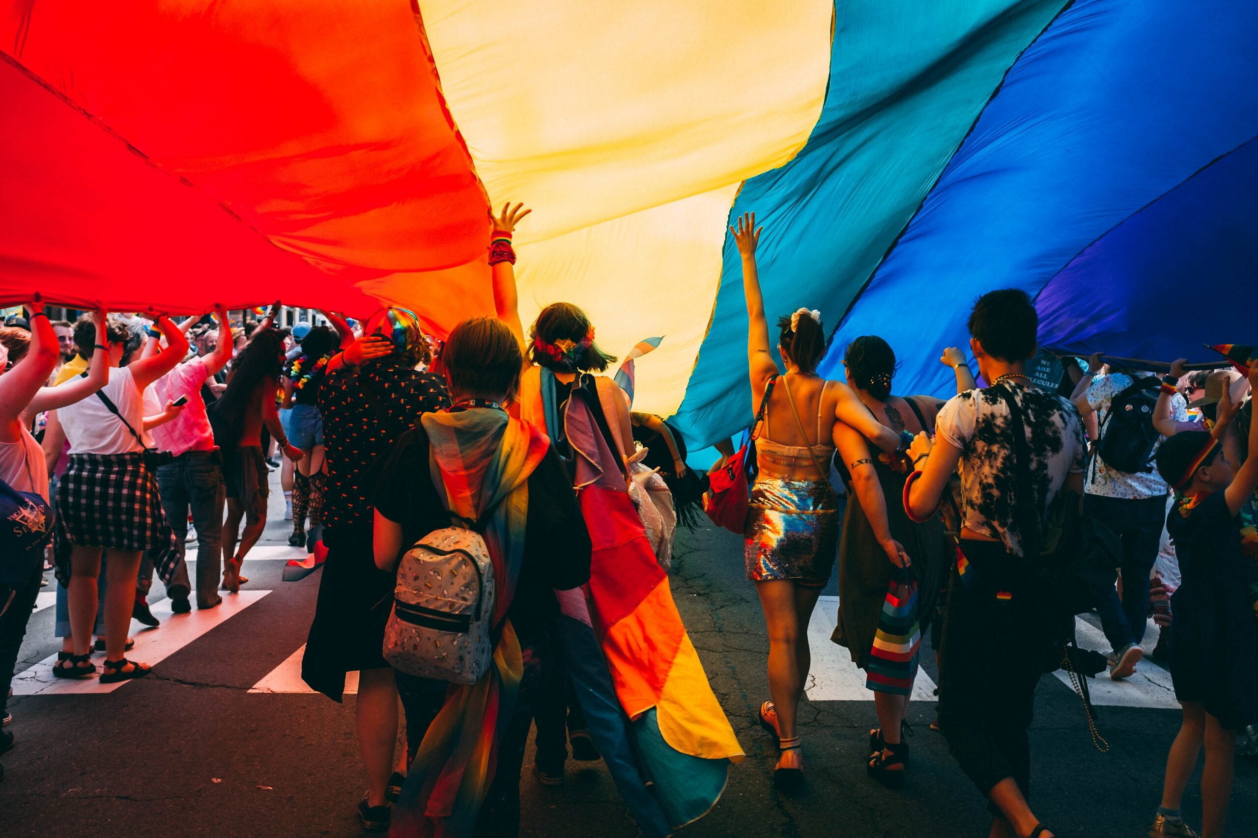 A group of people walking together under a rainbow flag